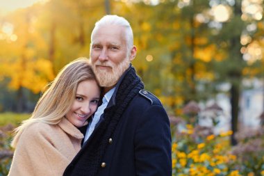 Joyful senior man cuddling his young granddaughter outdoors