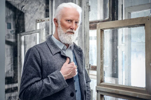 Elégant homme âgé habillé en manteau contre beaucoup de fenêtres — Photo