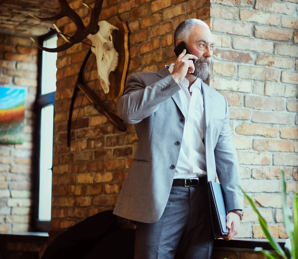 Elegant old man talking on mobile phone in office —  Fotos de Stock