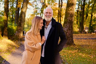Cheerful granddaughter and grandfather on walk in autumnal wood
