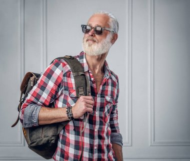 Beyaz duvarda güneş gözlüklü şık bir son sınıf öğrencisi.