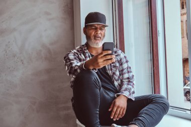 Cep telefonlu şık bir üst sınıf öğrencisi pencere kenarında oturuyor.