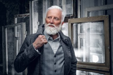 Bir sürü pencereye karşı şık saç stili olan yaşlı bir adam.