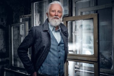 Bir sürü pencereye karşı şık saç stili olan yaşlı bir adam.