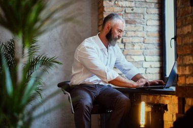 Ev ofisinde çalışan laptoplu yaşlı bir serbest çalışan.