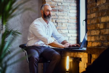 Ev ofisinde çalışan laptoplu yaşlı bir serbest çalışan.