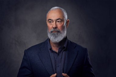 Koyu renk takım elbiseli, sakallı, şık bir ihtiyar.