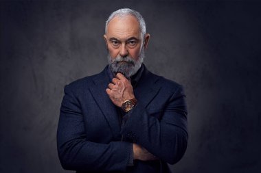 Eli çenesinin altında dalgın yaşlı bir adam.