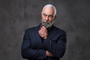 Eli çenesinin altında dalgın yaşlı bir adam.