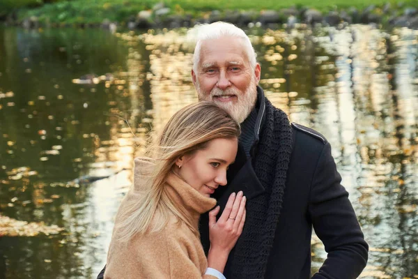 Старший мужчина со своей молодой девушкой на берегу озера — стоковое фото