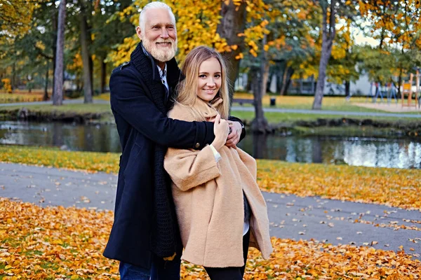 Старший мужчина и его девушка на прогулке в Осеннем парке — стоковое фото
