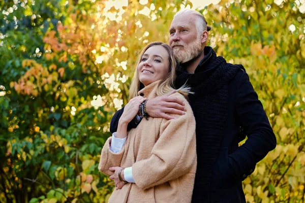 Couple of elderly man and young woman in autum — стоковое фото