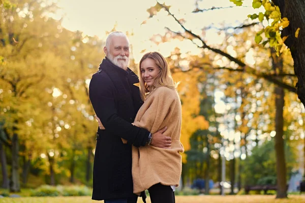 Обнимать старика и молодую женщину на открытом воздухе осенью в дневное время — стоковое фото