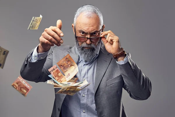 Rich elderly man throwing money against grey background — 스톡 사진