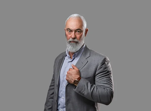 Бородатий старий одягнений у сірий костюм дивиться на камеру — стокове фото