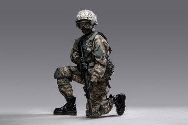 Tüfekli modern kadın gri arka planda oturuyor.