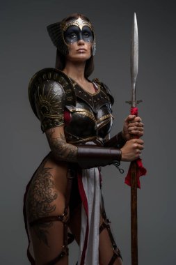 Gri arka planda mızrağı olan yaşlı kadın savaşçı.