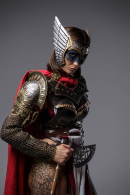 Gri arka planda baltalı vahşi bir kadın dövüşçü.