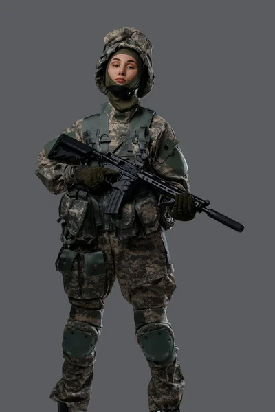 Mulher orgulhosa com rifle posando contra fundo cinza — Fotografia de Stock