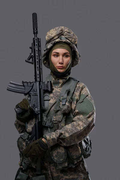 Soldado do exército feminino com rifle contra fundo cinza — Fotografia de Stock