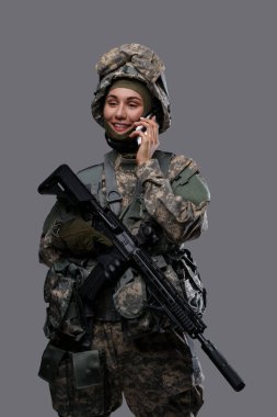 Gri arka planda cep telefonu olan mutlu asker kadın.