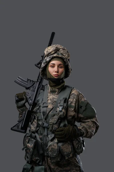 Soldado feminino olhando para a câmera contra fundo cinza — Fotografia de Stock