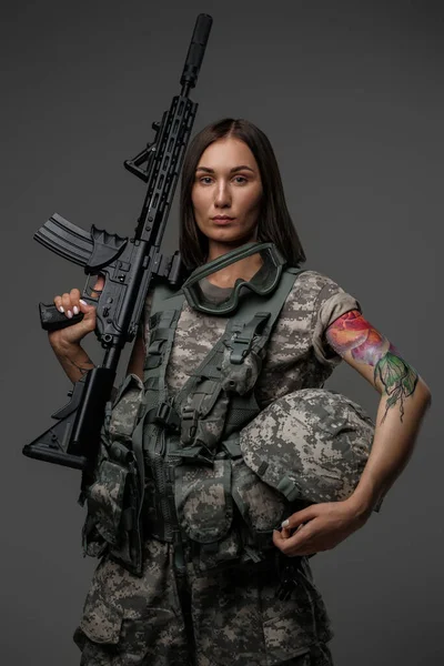 Atraktivní voják žena s puškou proti tmavému pozadí — Stock fotografie
