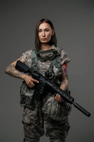 Militärangehörige mit braunen Haaren und Gewehr vor dunklem Hintergrund — Stockfoto