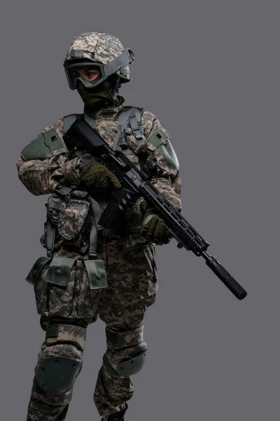 Forças especiais servicewoman segurando rifle contra fundo cinza — Fotografia de Stock