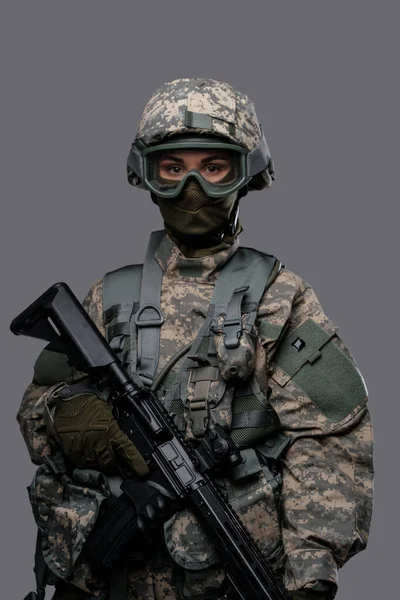 Профессиональная боевая женщина с винтовкой изолирована на сером фоне — стоковое фото