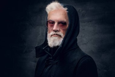 Güneş gözlüğü takmış, kapüşonlu, koyu renk arka planda bir hippi fotoğrafı..