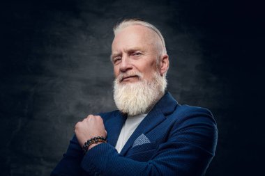 Koyu mavi takım elbiseli, koyu renk arka planda şık saç stili olan yaşlı bir adamın stüdyo fotoğrafı..