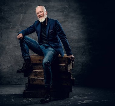 Yakacak odunlukta oturan uzun sakallı ve şık saç stili olan yakışıklı bir adamın fotoğrafı..