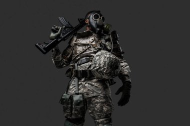 Stüdyo çekiminde, gri arka planda, omzunda tüfek tutan siyah bir asker görülüyor..