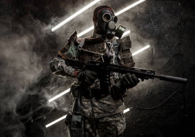 Gaz maskeli ve tüfekli bir Afrikalı askeri vurularak esmer arka plana karşı neon ve dumanlı.