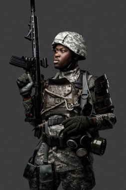 Modern kamuflaj üniforması giymiş, elinde tüfek tutan Afrikalı bir askerin portresi..