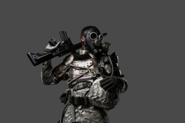 Stüdyo çekiminde, gri arka planda, omzunda tüfek tutan siyah bir asker görülüyor..