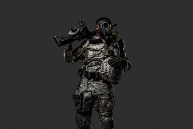 Stüdyo çekiminde, gri arka planda, omzunda tüfek tutan siyah bir asker görülüyor..