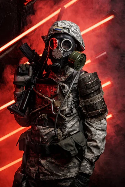 Art of soldier dressed in armor and gas mask against red background with smoke and neon.