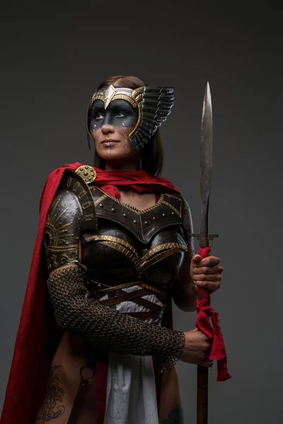 工作室拍摄的古代女兵身穿钢制盔甲 手持斗篷长矛 — 图库照片