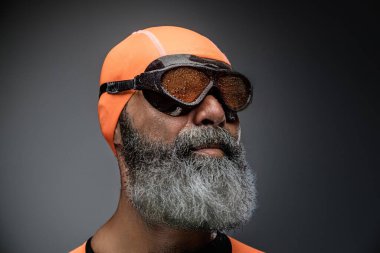 Turuncu mayo ve gözlük giymiş, uzun sakallı, aktif yaşlı bir adamın portresi..