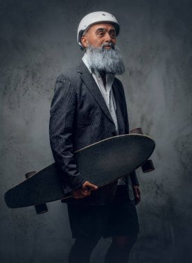 Stüdyoda, elinde kaykayla şık bir kıyafet giymiş son sınıf öğrencisinin fotoğrafı..