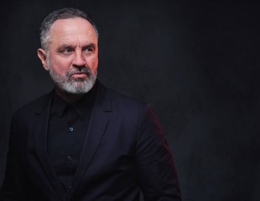 Siyah ceket ve siyah gömlek giymiş, sakallı, şık, yaşlı bir adamın stüdyo fotoğrafı..