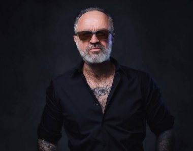 Siyah gömlek ve güneş gözlüğü takmış, dövmeli, vahşi maço bir fotoğraf stüdyosu..