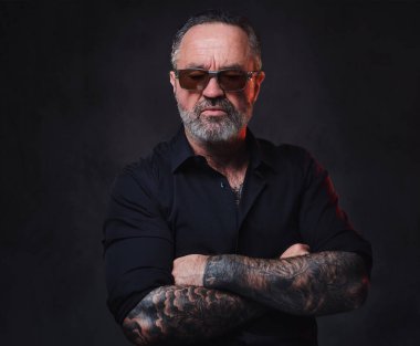 Siyah gömlekli, güneş gözlüklü ve dövmeli vahşi yaşlı maço portresi..