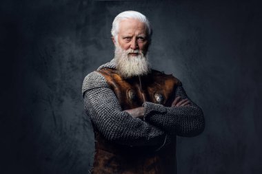 Zırhlı giysiler içinde siyah arka plana poz veren gri saçlı ortaçağ askerinin fotoğrafı..