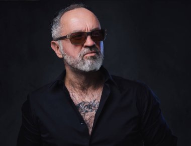 Siyah gömlek ve güneş gözlüğü takmış, dövmeli, vahşi maço bir fotoğraf stüdyosu..