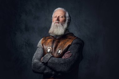 Zırhlı giysiler içinde siyah arka plana poz veren gri saçlı ortaçağ askerinin fotoğrafı..