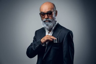 Şık takım elbiseli ve banka kartlı güneş gözlüklü kıdemli işadamının fotoğrafı..