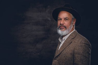 Takım elbiseli ve siyah arka planda poz veren mutlu yaşlı adamın portresi..